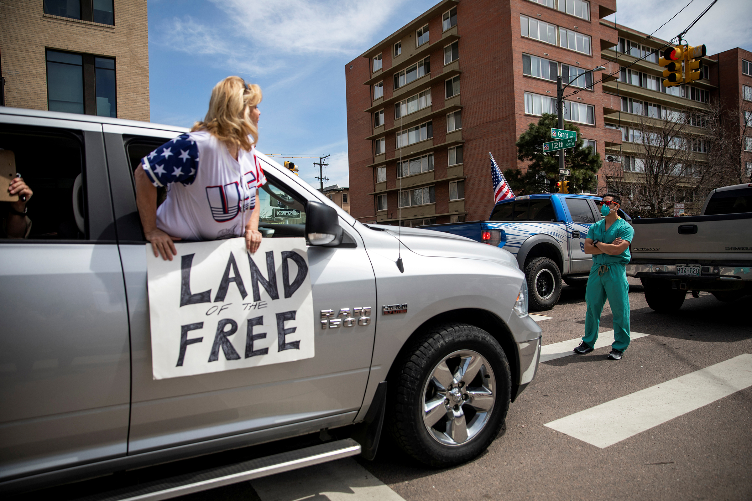 Health care workers stand in the street as a counter-protest to those demanding the stay-at-home order be lifted in Denver